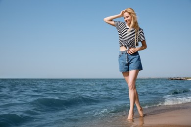 Beautiful young woman near sea on sunny day in summer, space for text