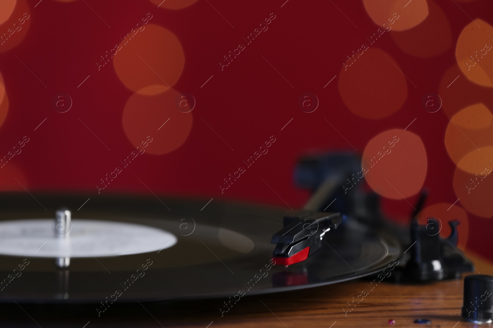 Photo of Vinyl record on turntable against blurred lights, closeup. Space for text