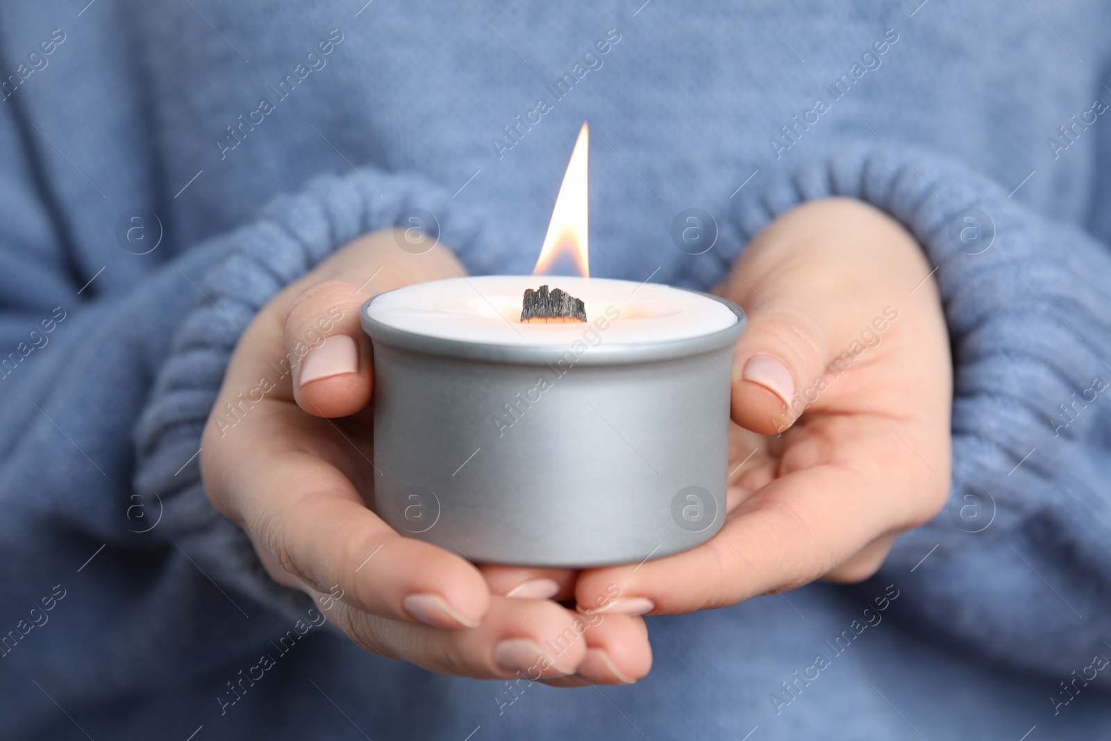 Photo of Woman holding burning candle with wooden wick, closeup