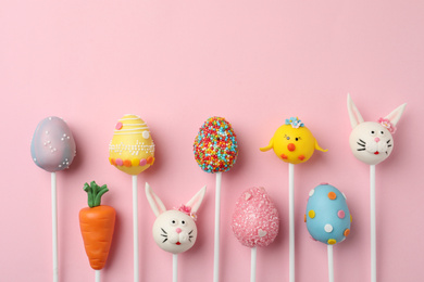 Photo of Delicious sweet cake pops for Easter celebration on pink background, flat lay