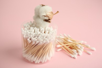 Photo of Container with cotton buds and flower on pink background