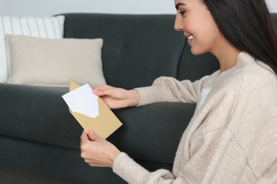 Photo of Happy woman reading greeting card on floor in living room