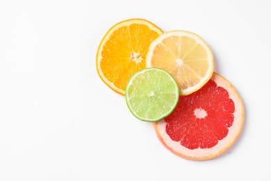 Photo of Slices of fresh ripe citrus fruits on white background, flat lay. Space for text