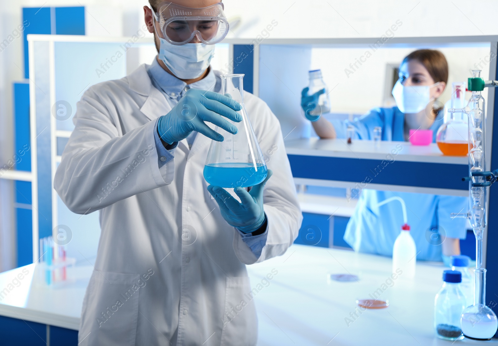 Photo of Scientist holding conical flask with blue liquid indoors. Laboratory analysis