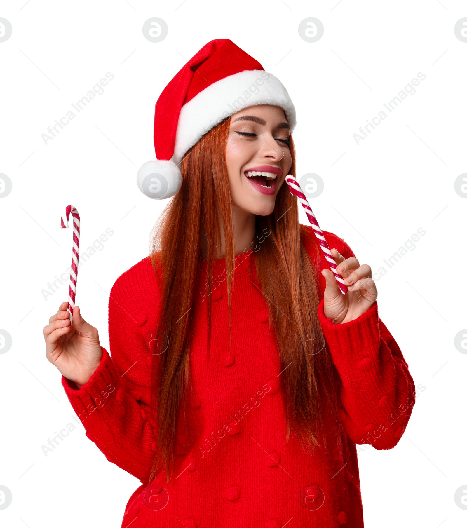 Photo of Young woman in red sweater and Santa hat with candy canes on white background. Christmas celebration