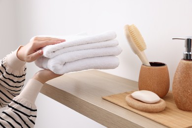 Photo of Bath accessories. Woman with stack of clean towels indoors, closeup