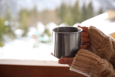 Woman with cup of tasty coffee outdoors on winter morning, closeup