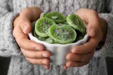 Woman holding bowl with slices of tasty kiwi, closeup. Dried fruit as healthy food