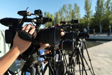 Photo of Operators with professional video cameras working outdoors on sunny day, closeup