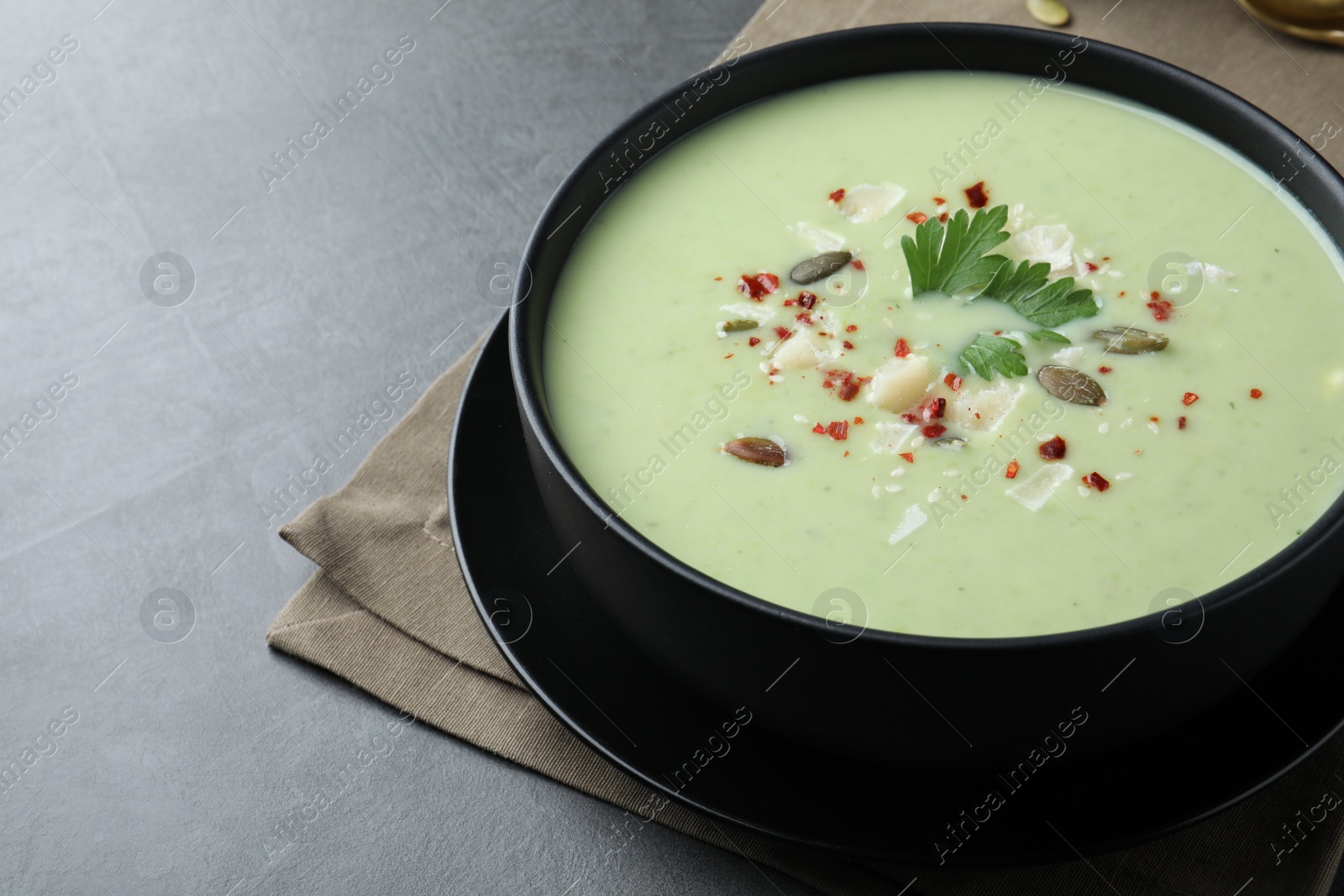 Photo of Bowl of delicious asparagus soup on dark table, space for text