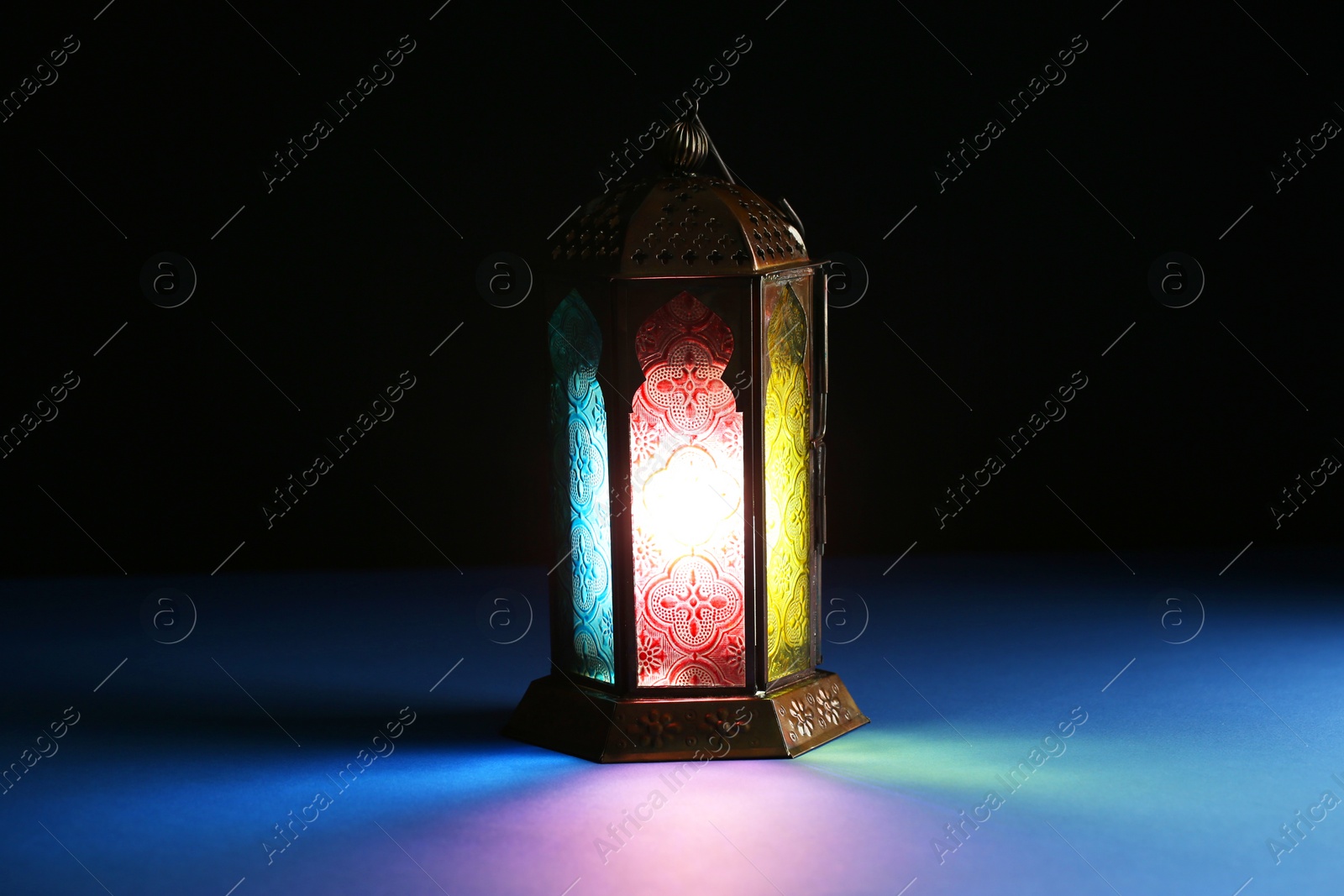 Photo of Decorative Arabic lantern on table against dark background. Space for text