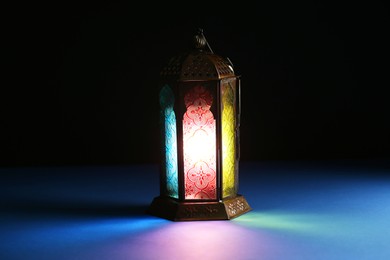 Photo of Decorative Arabic lantern on table against dark background. Space for text