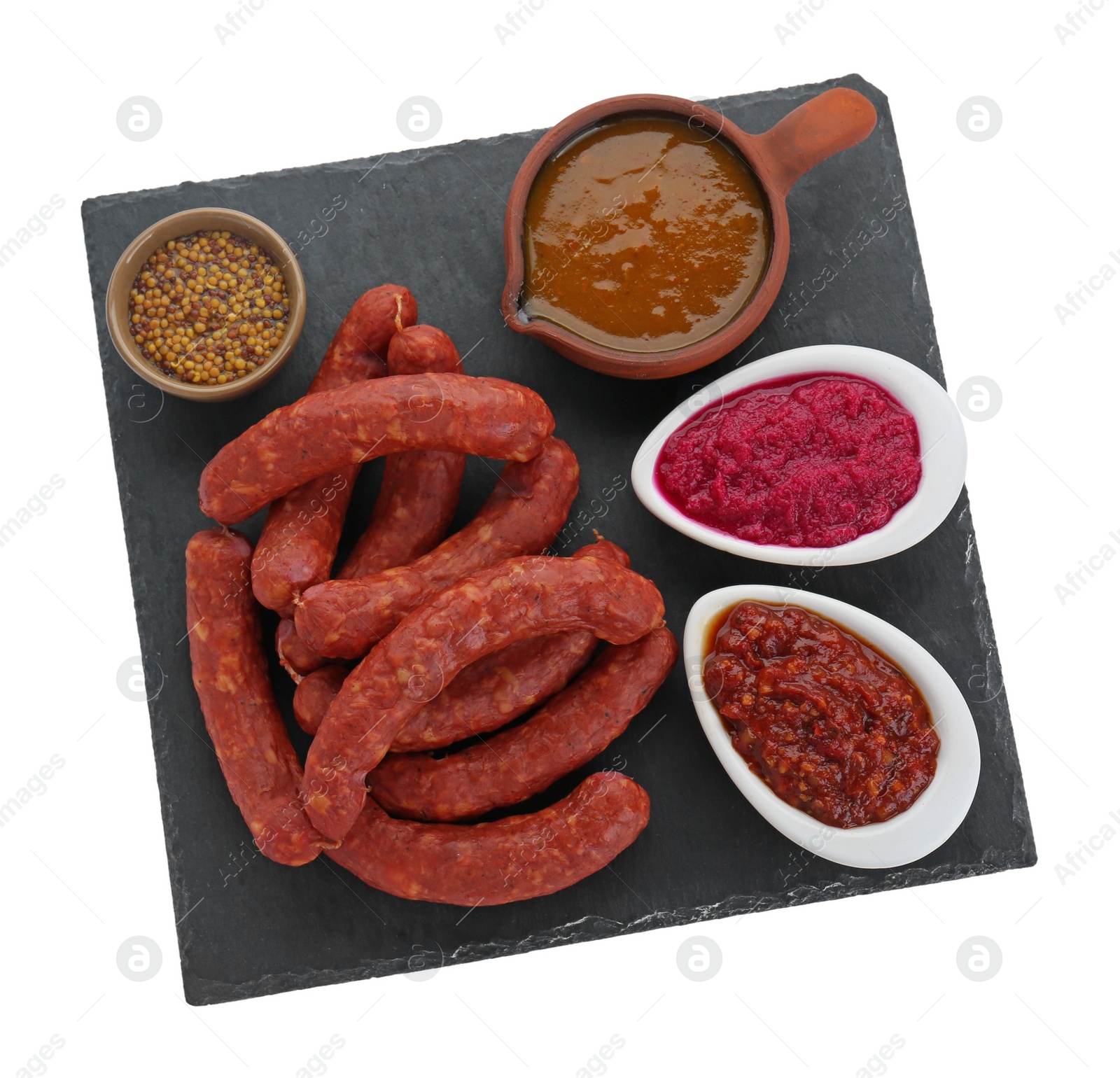 Photo of Slate plate with tasty sausages and different sauces isolated on white, top view. Meat product