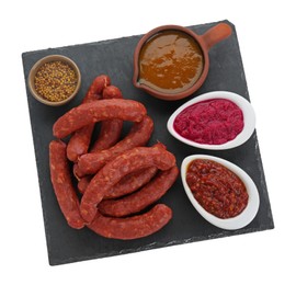 Photo of Slate plate with tasty sausages and different sauces isolated on white, top view. Meat product