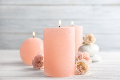 Burning candles, spa stones and flowers on table