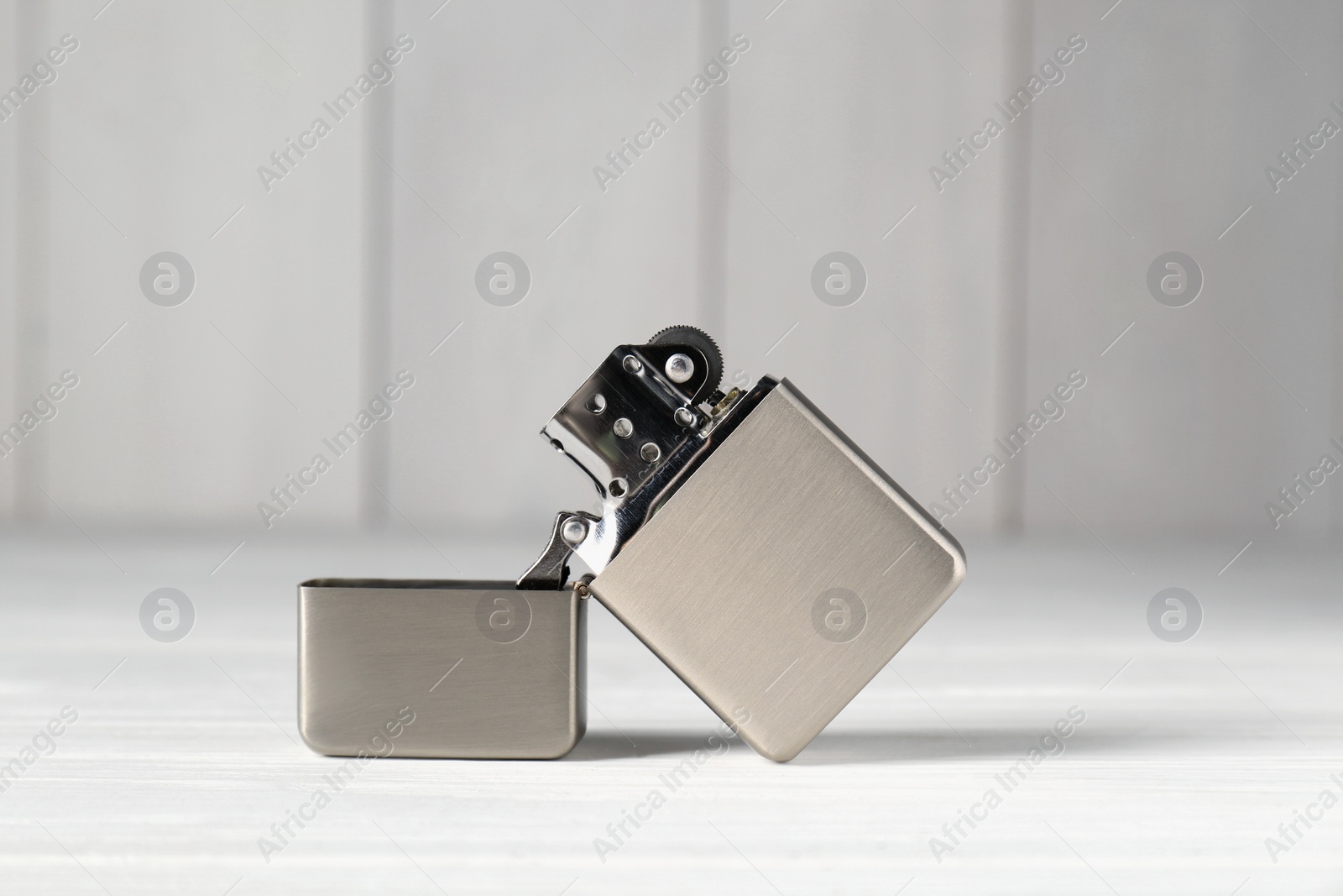 Photo of Gray metallic cigarette lighter on white wooden table, closeup