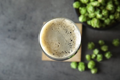 Flat lay composition with tasty beer and fresh green hops on grey background