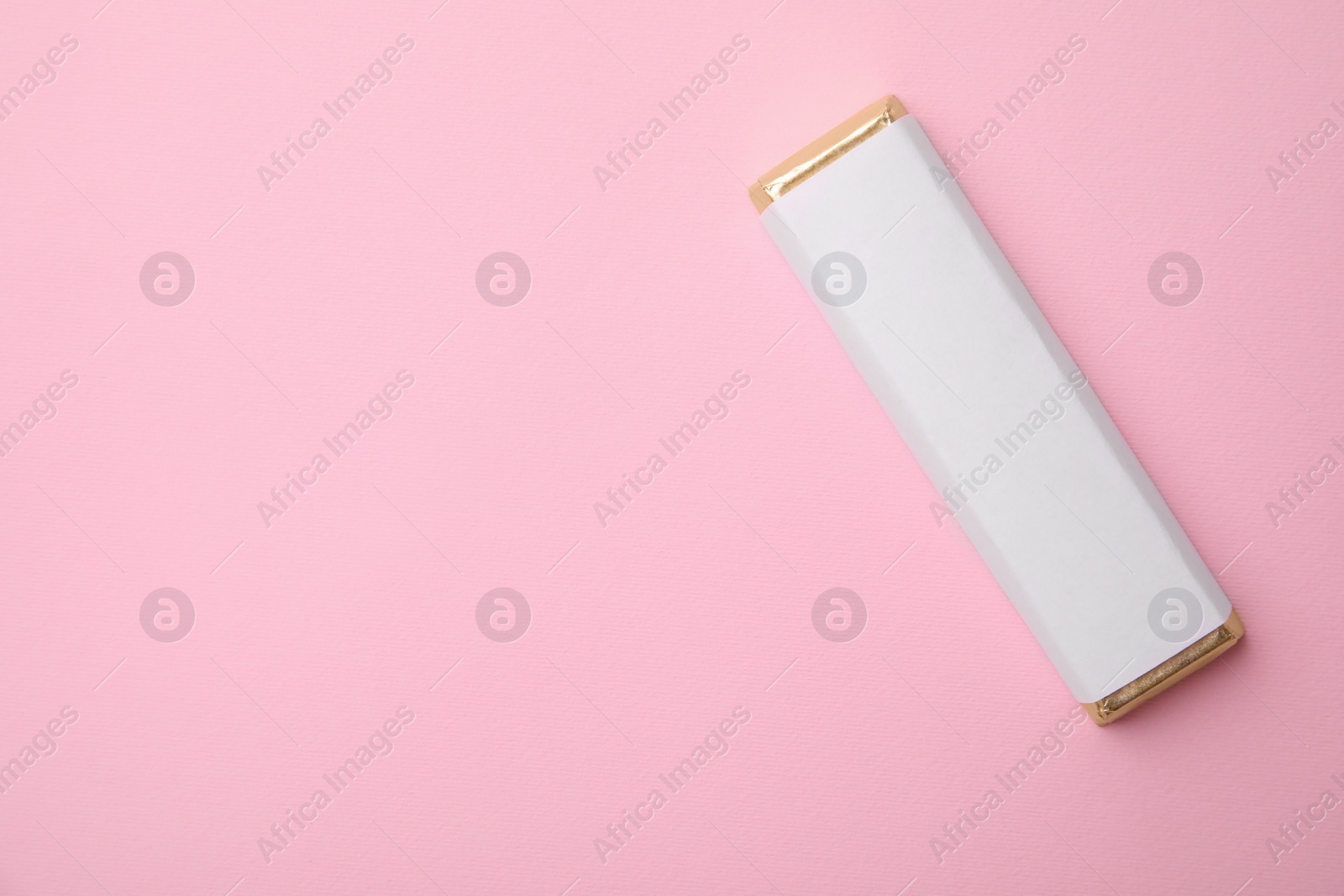 Photo of Tasty chocolate bar in package on pink background, top view. Space for text