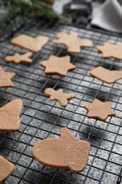 Photo of Homemade Christmas cookies. Baking rack with raw gingerbread biscuits on grey table, closeup