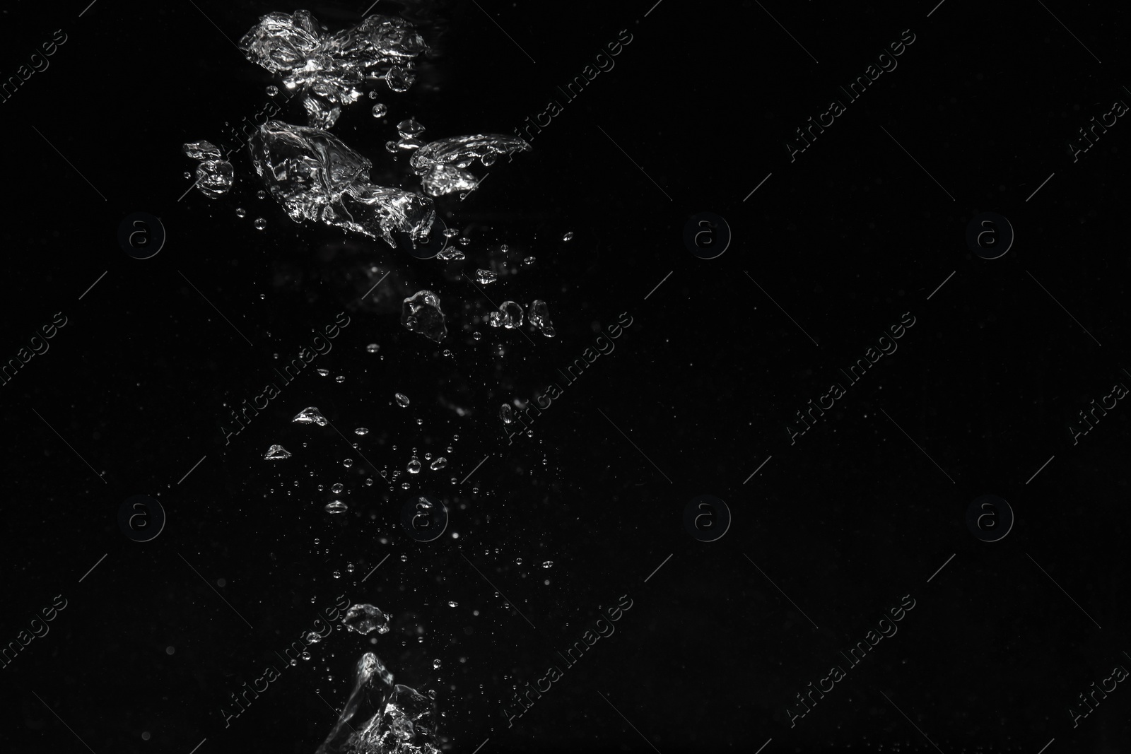 Photo of Air bubbles in water on black background, space for text