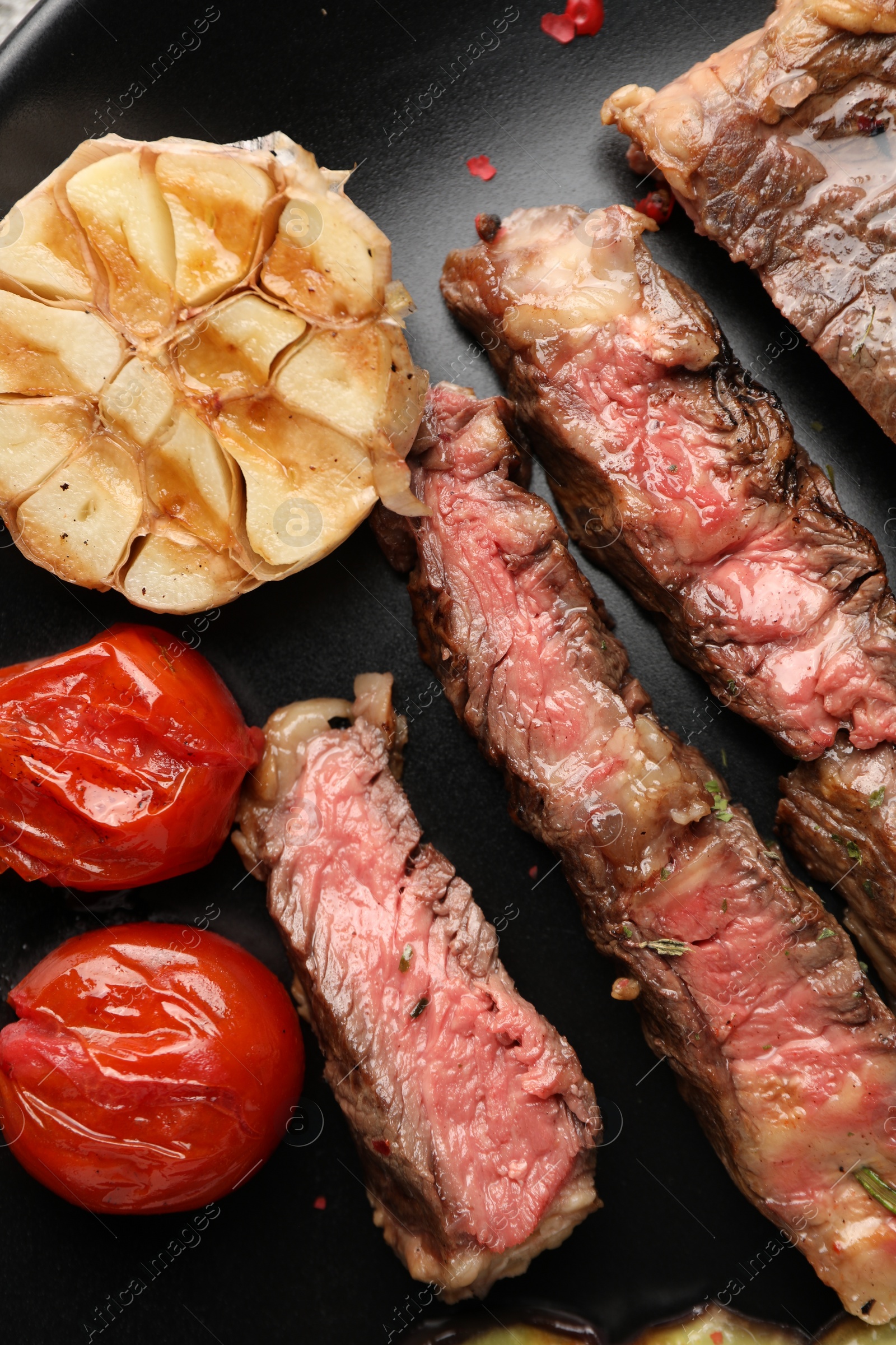 Photo of Delicious grilled beef steak with vegetables and spices on plate, top view