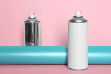 Photo of Cans of different spray paints on color background