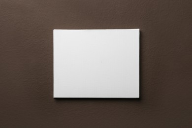 Photo of Blank canvas on brown wall. Space for design