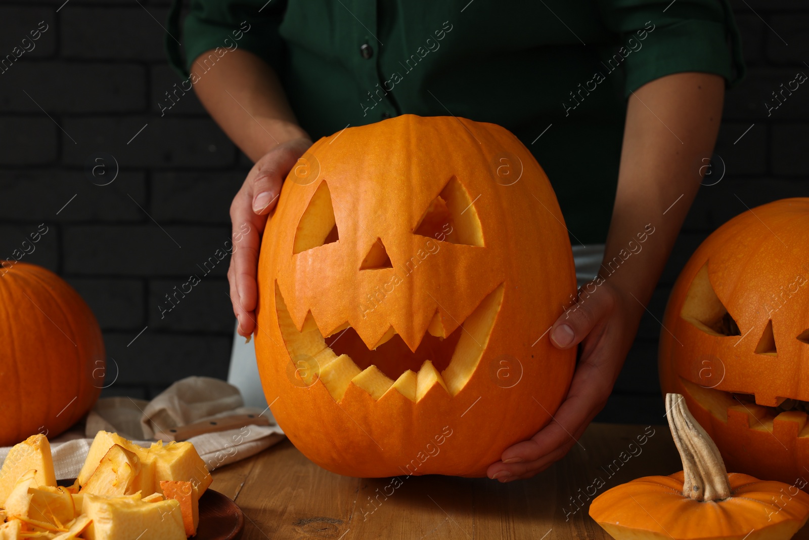 Photo of Woman with carved pumpkins at wooden table, closeup. Halloween celebration