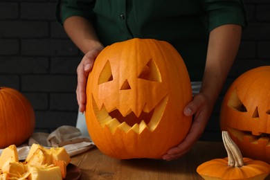 Photo of Woman with carved pumpkins at wooden table, closeup. Halloween celebration