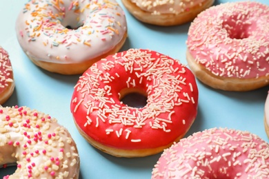 Delicious glazed doughnuts with sprinkles on color background