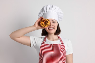 Happy confectioner with donut on light grey background