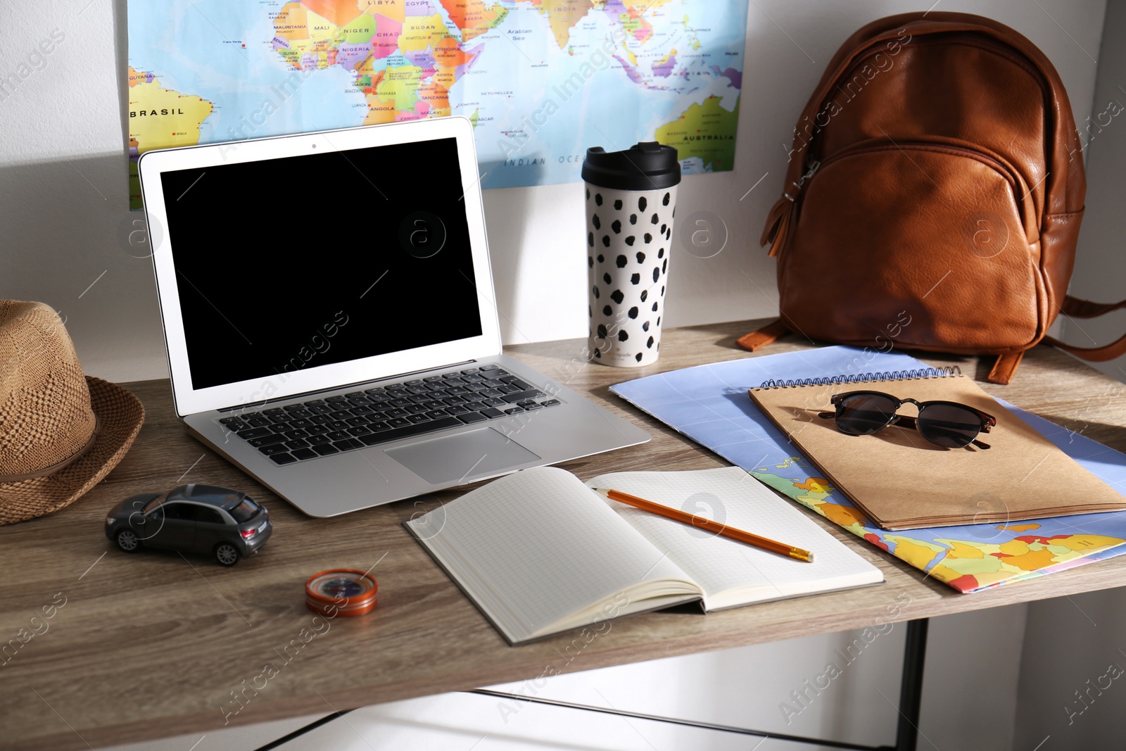 Photo of Laptop, notebook and travel accessories on wooden table. Planning summer vacation trip