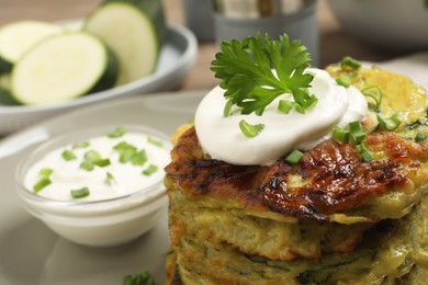 Photo of Delicious zucchini fritters with sour cream plate, closeup. Space for text