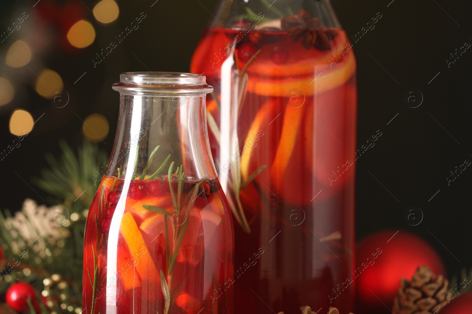 Photo of Glass bottles of aromatic punch drink on dark background, closeup