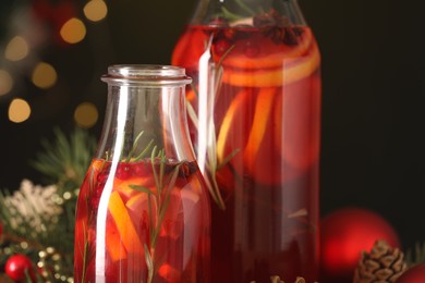 Glass bottles of aromatic punch drink on dark background, closeup