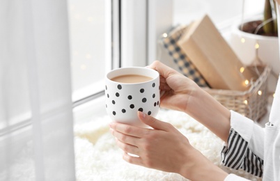 Photo of Morning of young woman with cup of hot coffee at home