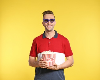 Photo of Man with 3D glasses and popcorn during cinema show on color background