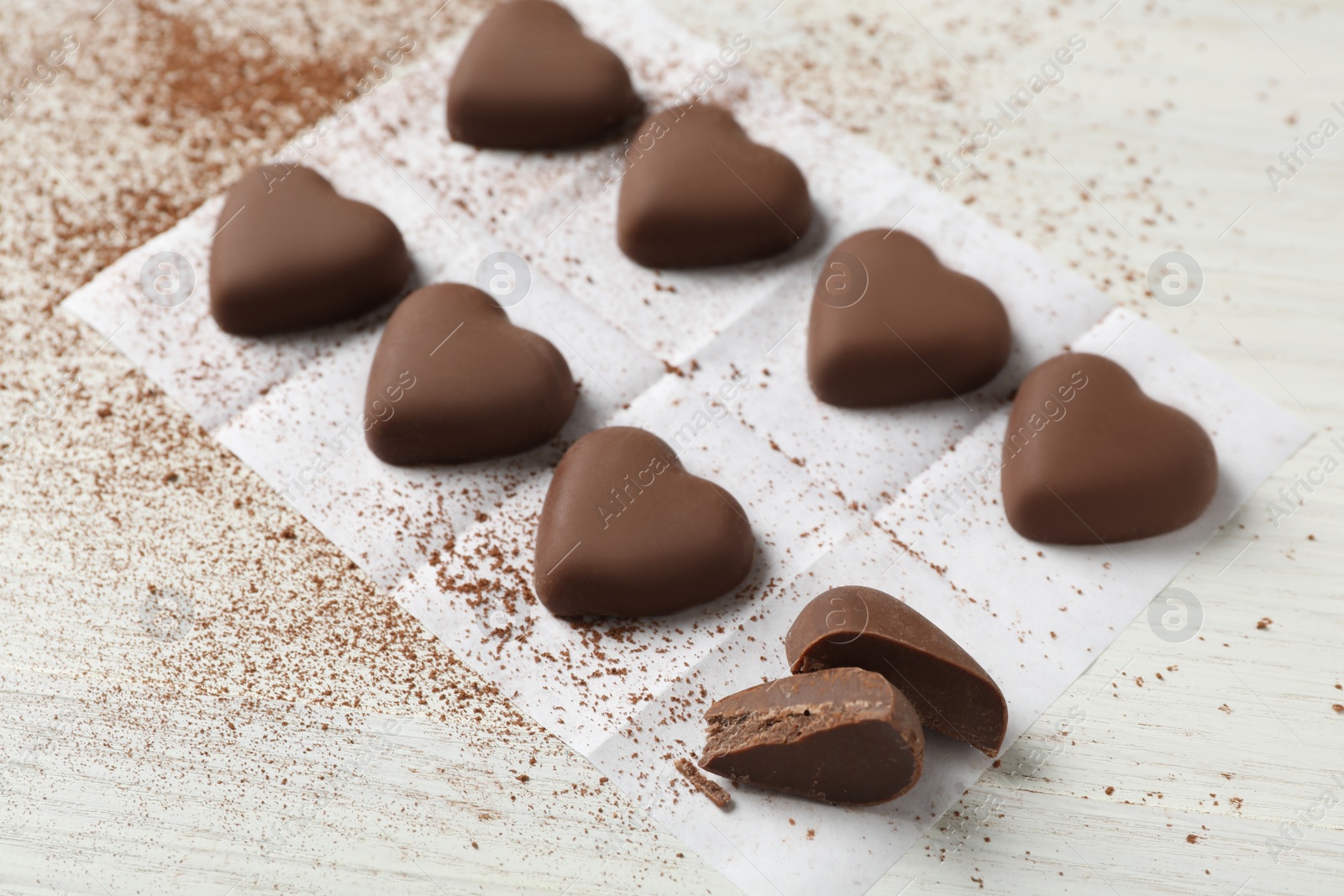 Photo of Beautiful heart shaped chocolate candies on white wooden table