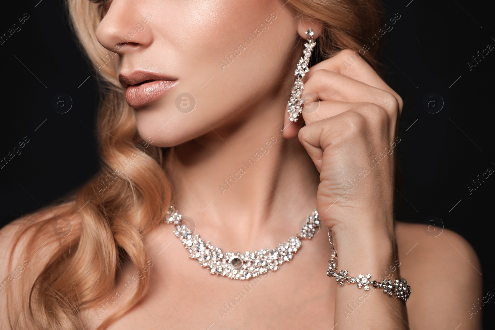 Photo of Beautiful young woman with elegant jewelry on dark background, closeup