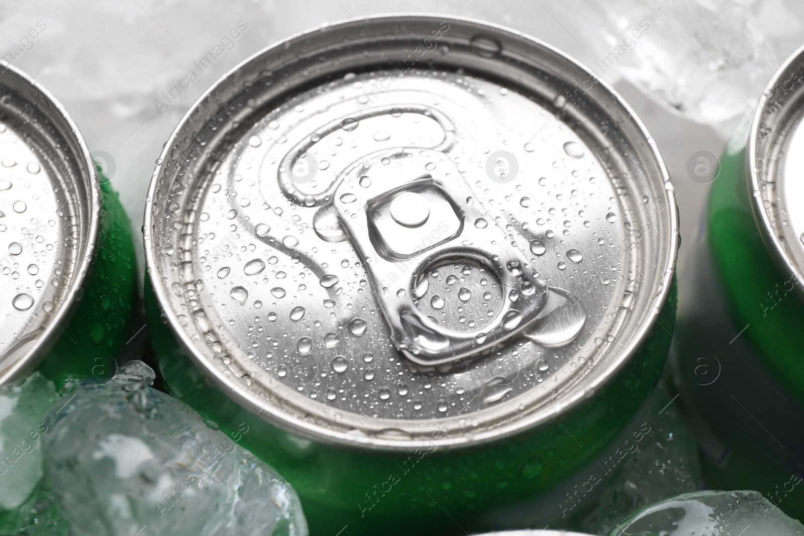 Photo of Energy drinks in wet cans and ice cubes, closeup