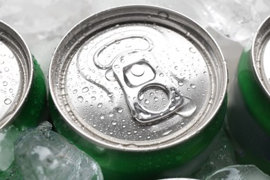 Energy drinks in wet cans and ice cubes, closeup