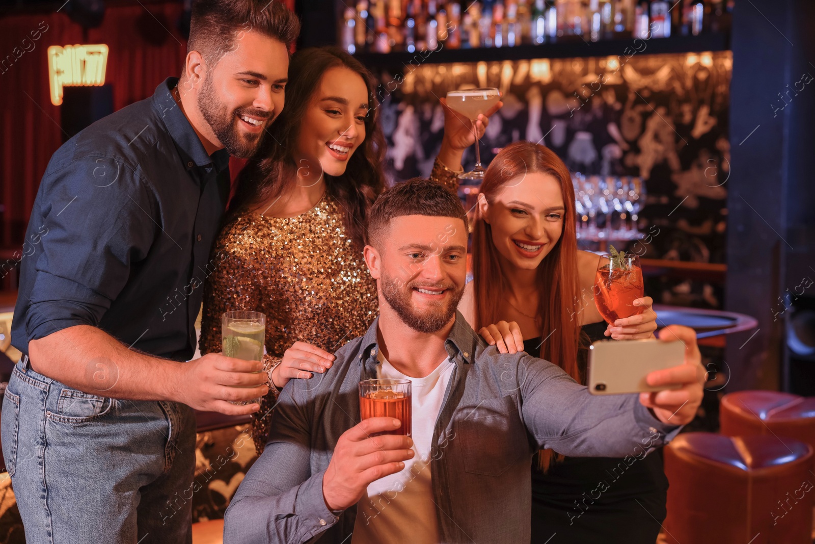 Photo of Happy friends with cocktails taking selfie together in bar