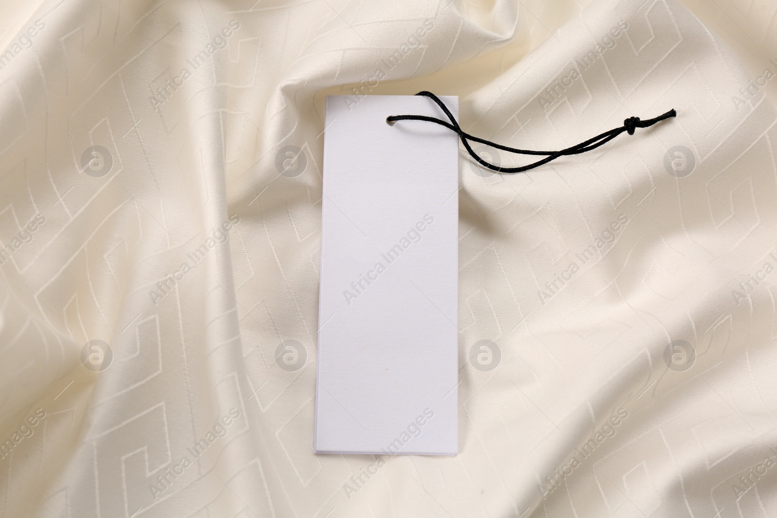 Photo of Blank tags on white fabric, top view. Space for text