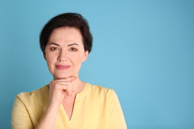 Portrait of charming mature woman with healthy beautiful face skin and natural makeup on blue background, space for text