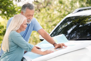 Photo of Senior couple with road map outdoors. Travelling by car