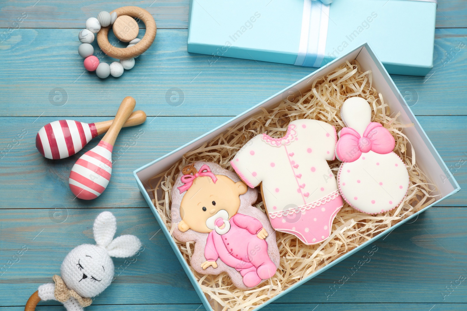 Photo of Set of baby shower cookies in gift box and accessories on turquoise wooden table, flat lay