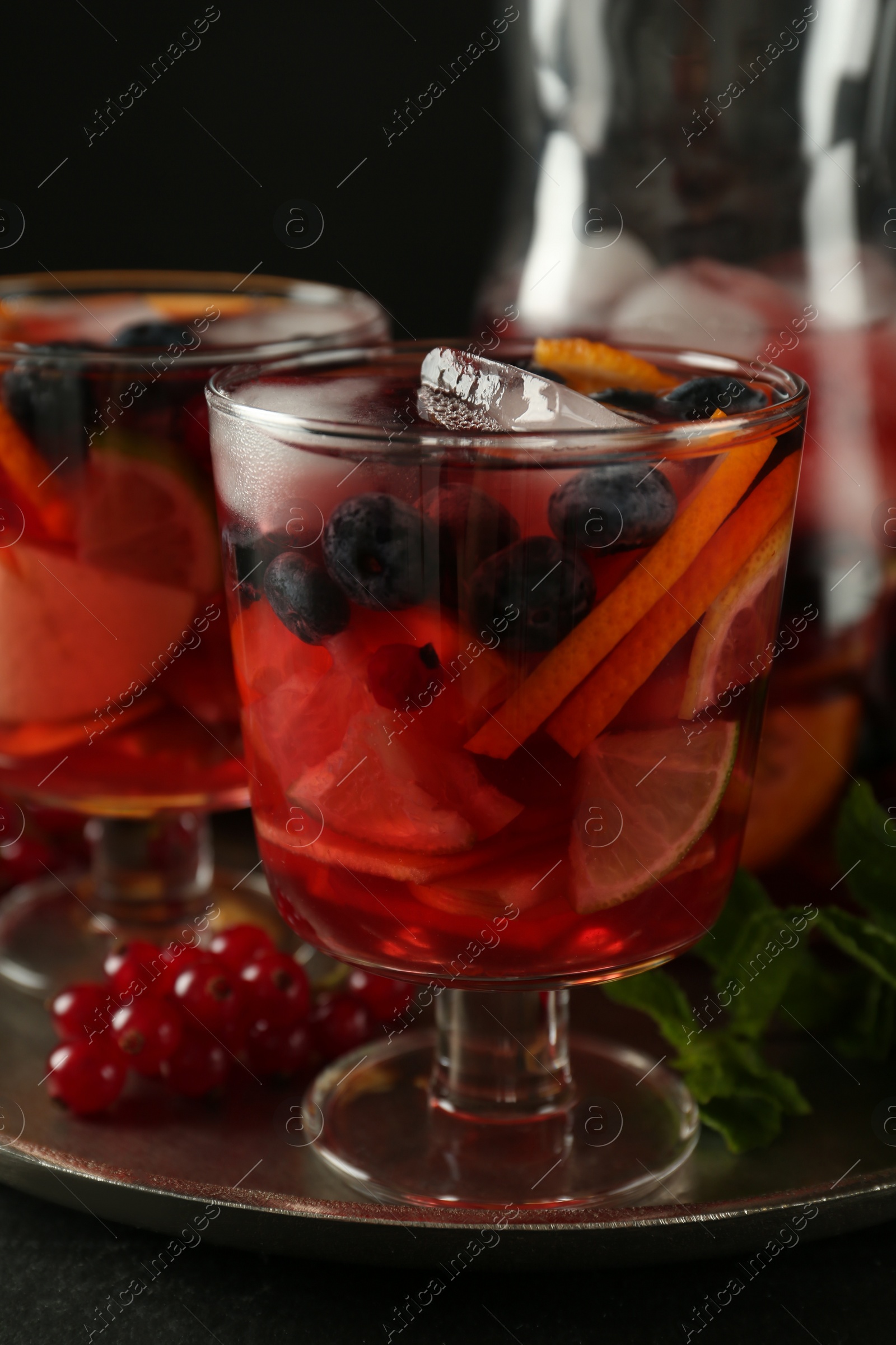 Photo of Glass of Red Sangria with fruits on black table