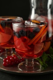 Photo of Glass of Red Sangria with fruits on black table