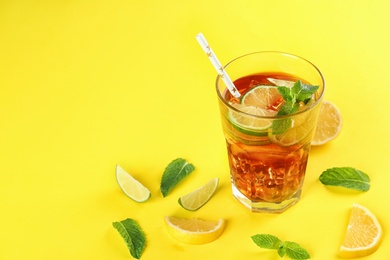 Photo of Glass of refreshing iced tea on yellow background. Space for text