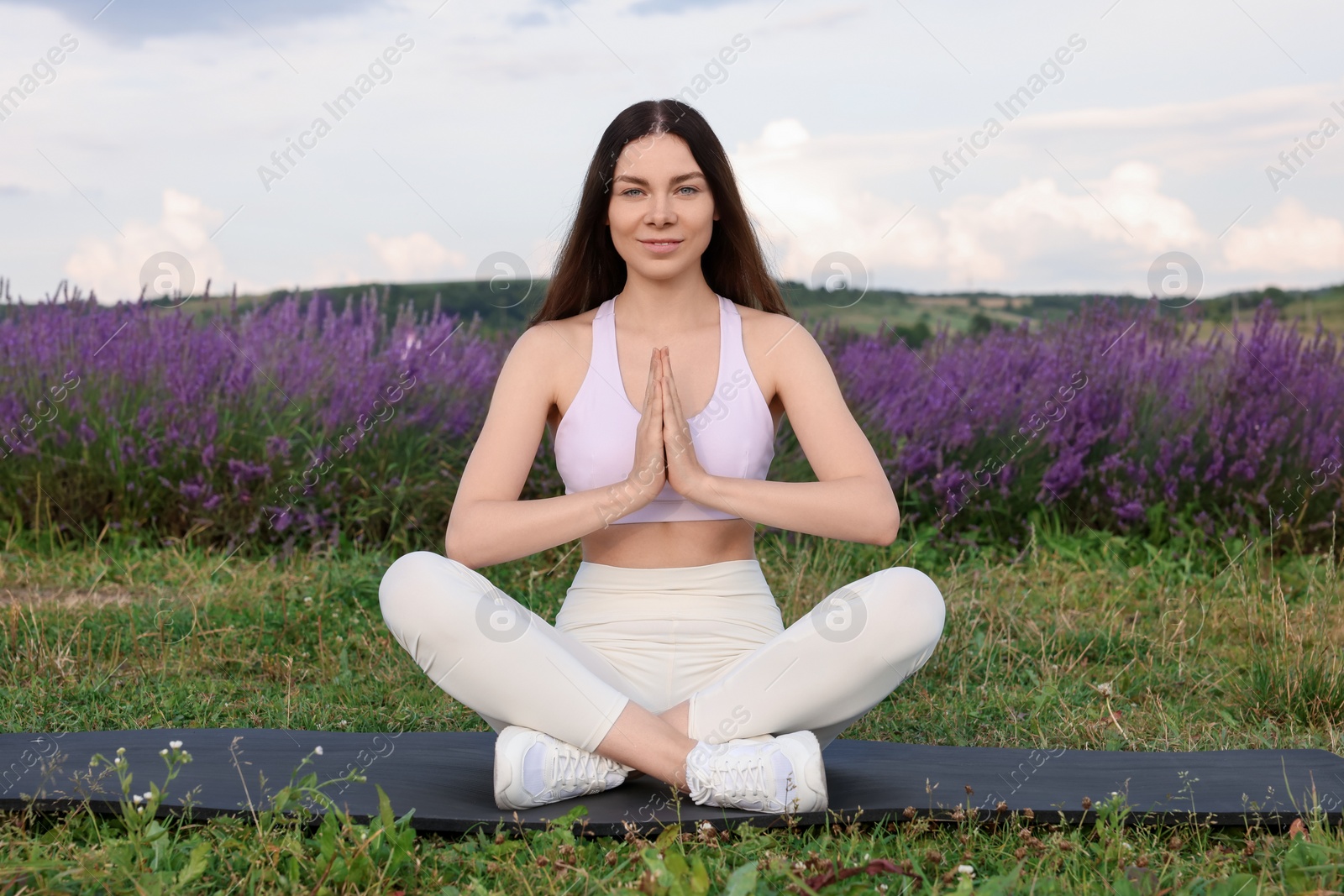 Photo of Smiling woman practicing yoga near lavender outdoors